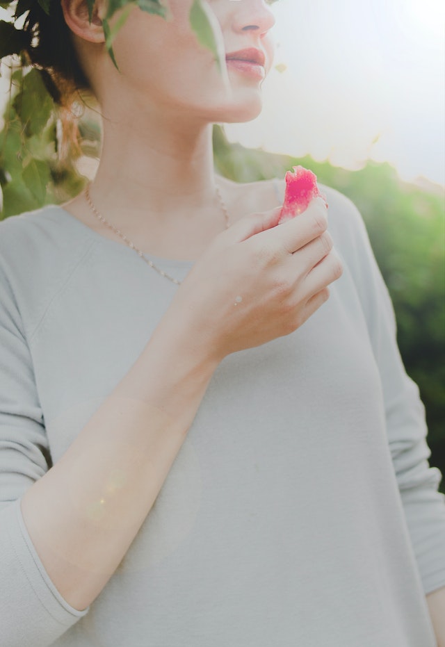 woman mindfully eating a piece of fruit in nature