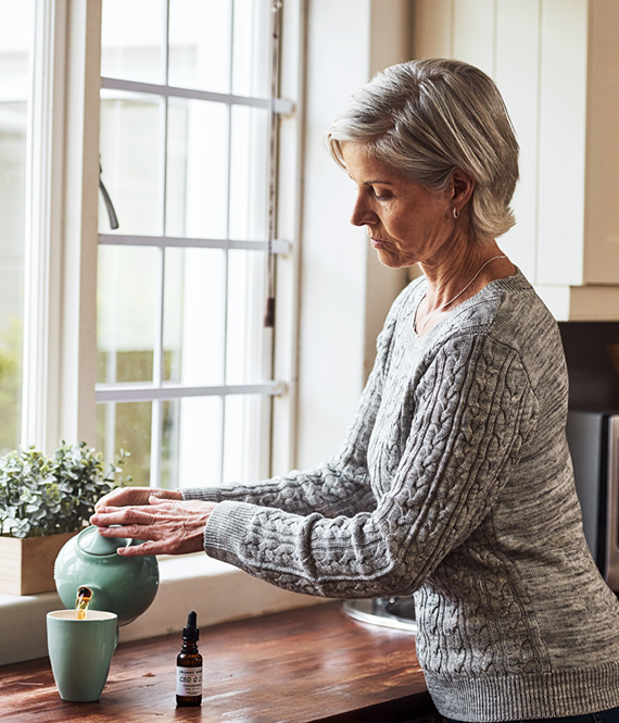 woman making a cup of chamomile tea with cbd oil