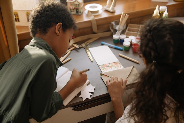 two kids making diy artwork for christmas cards