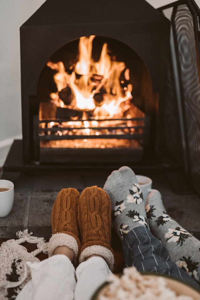two people with socks out laying by the fireplace