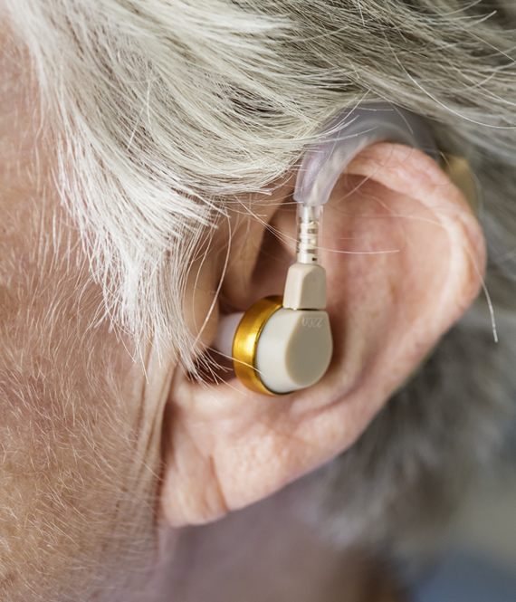elderly woman wearing hearing aid to help hearing loss symptoms