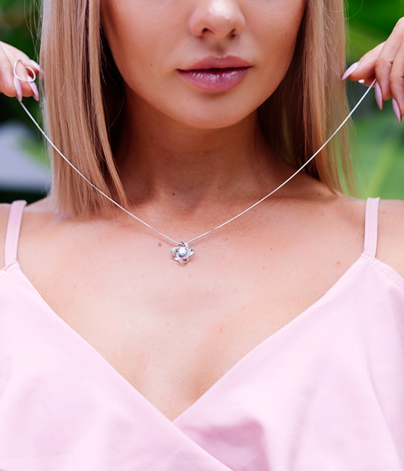 woman putting on jeweled necklace after using jewelry care tips