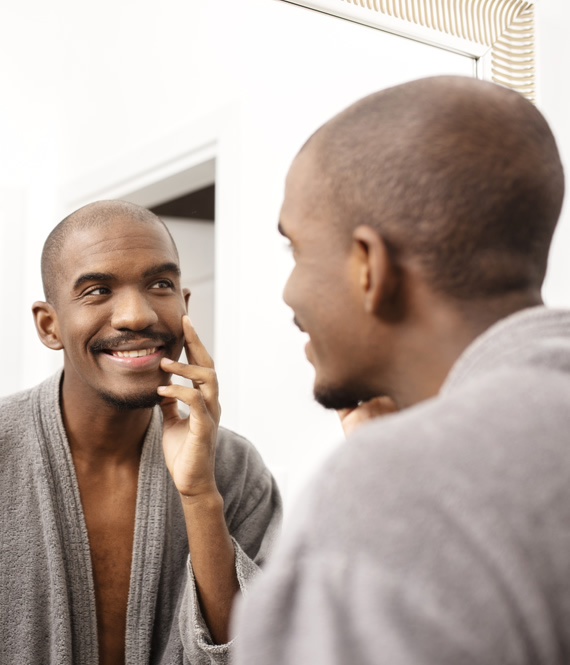 middle aged African American man inspecting hair loss situation in mirror