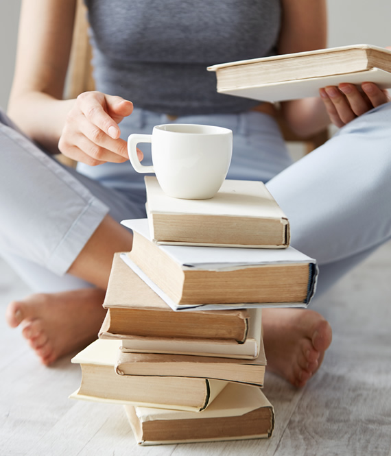 young person reads psychology books and drinks coffee