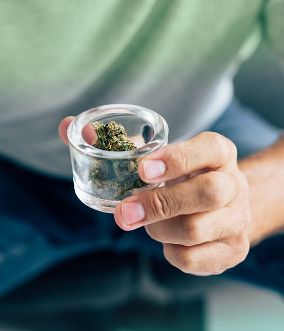 person holds medical cannabis in a glass container